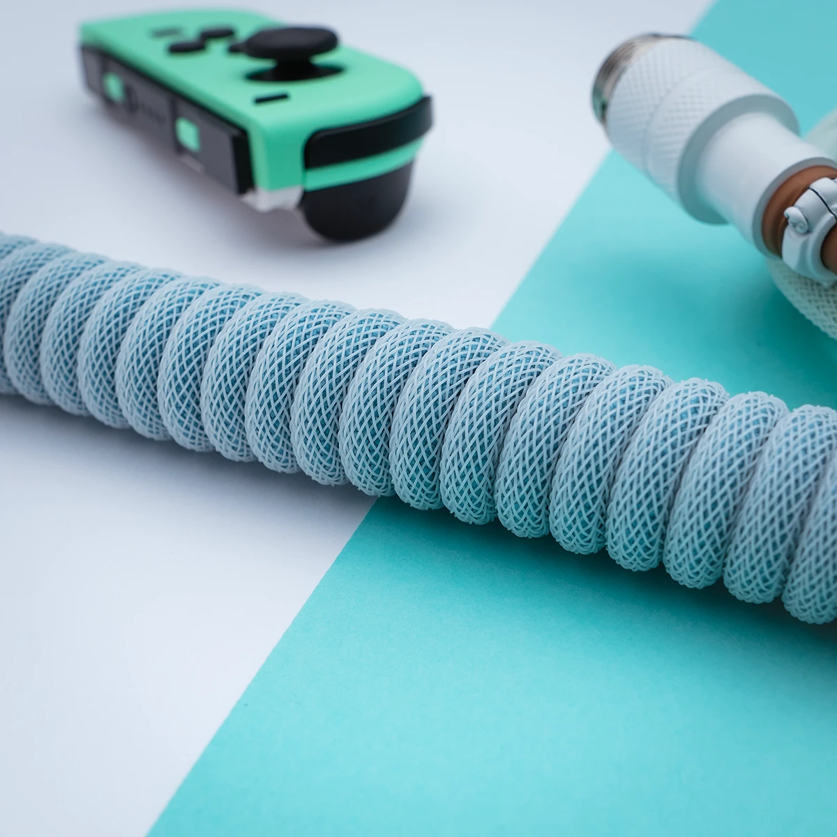 Custom PBT Islander Keyboard Cable features a sleek, light blue braided coil, a detachable USB-C connector, and high-quality CNC metal housing for durability.