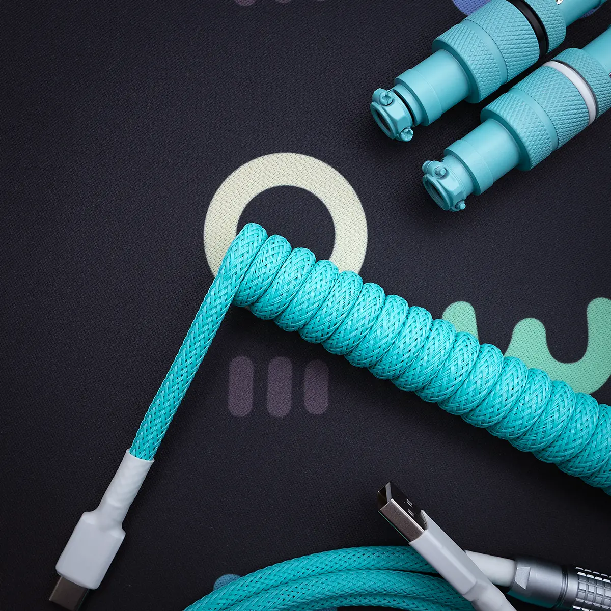 Coiled turquoise keyboard cable featuring USB-C and micro-USB connectors. The paracord finish and CNC metal housing offer durability and style.