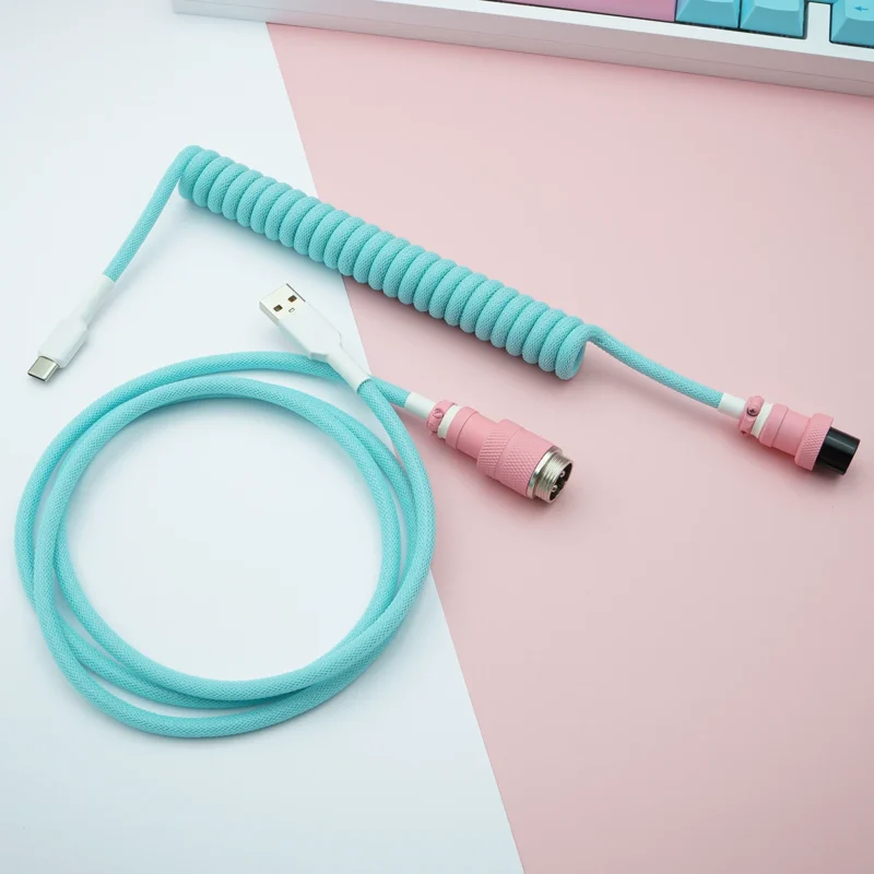 Custom keyboard cable featuring a coiled section in light blue, USB-C and aviator connectors, with pink accents and durable paracord braiding.