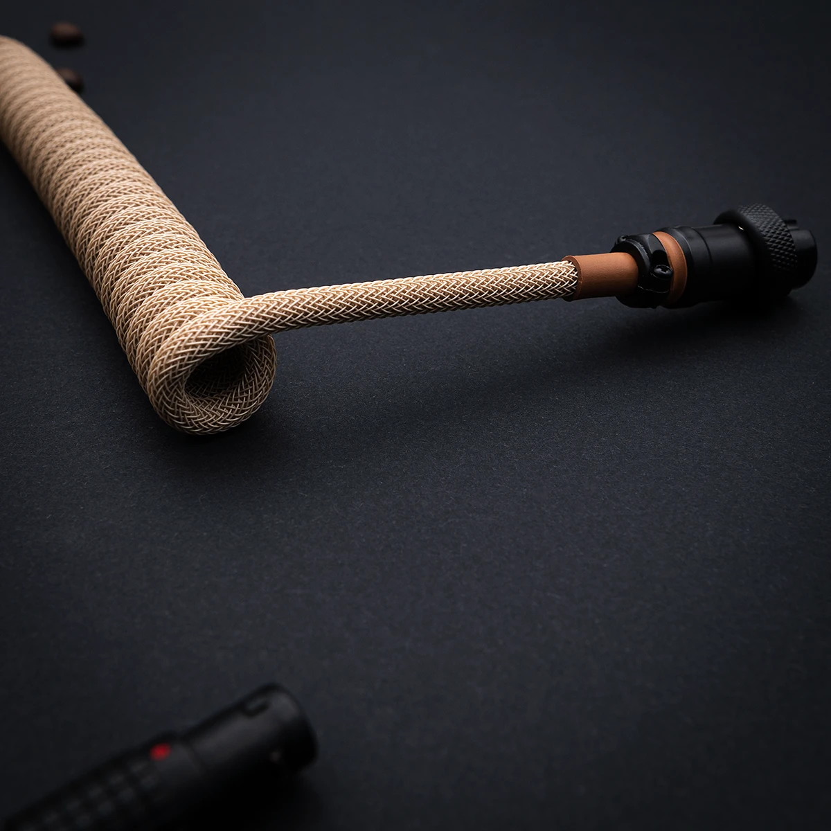 Coiled paracord keyboard cable features a sleek braiding in beige, with a detachable aviator connector for versatility and high-quality finish.
