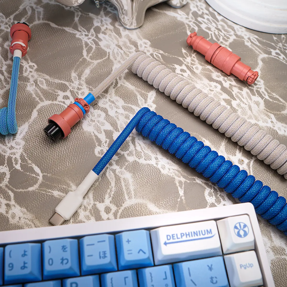 A vibrant blue coiled keyboard cable features USB-C and aviator connectors, braided for durability. Perfect for custom setups, showcasing stylish textures.