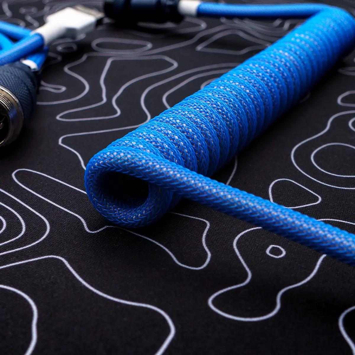 Coiled blue paracord keyboard cable with braided texture, featuring detachable connectors and high-quality CNC metal housing for durability.