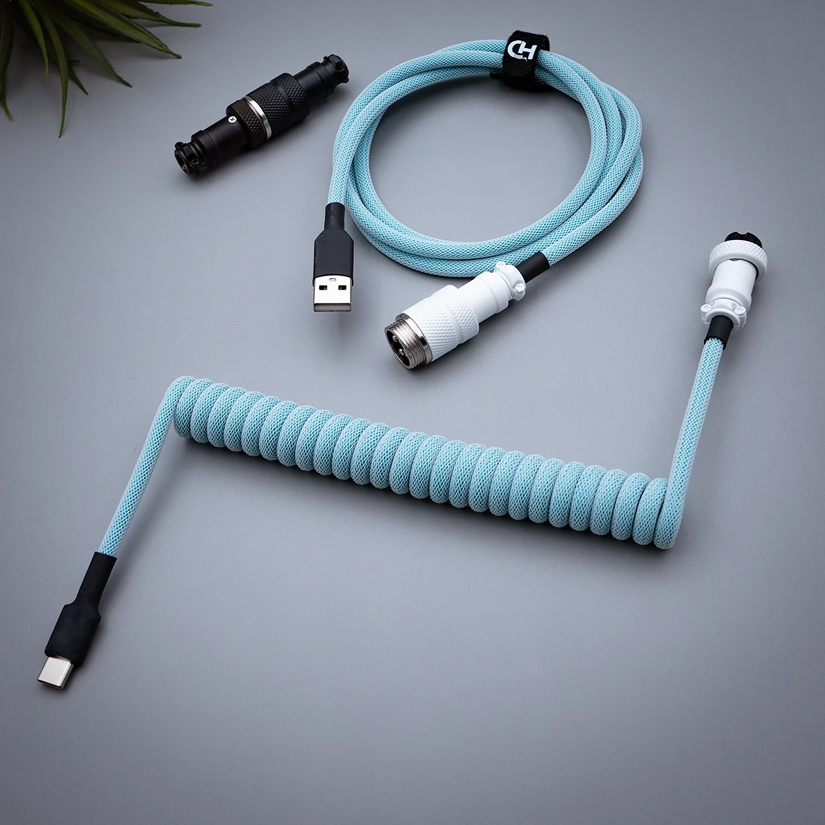 Coiled light blue keyboard cable featuring USB-C and aviator connectors, paracord design, and quality heatshrink for durable performance.