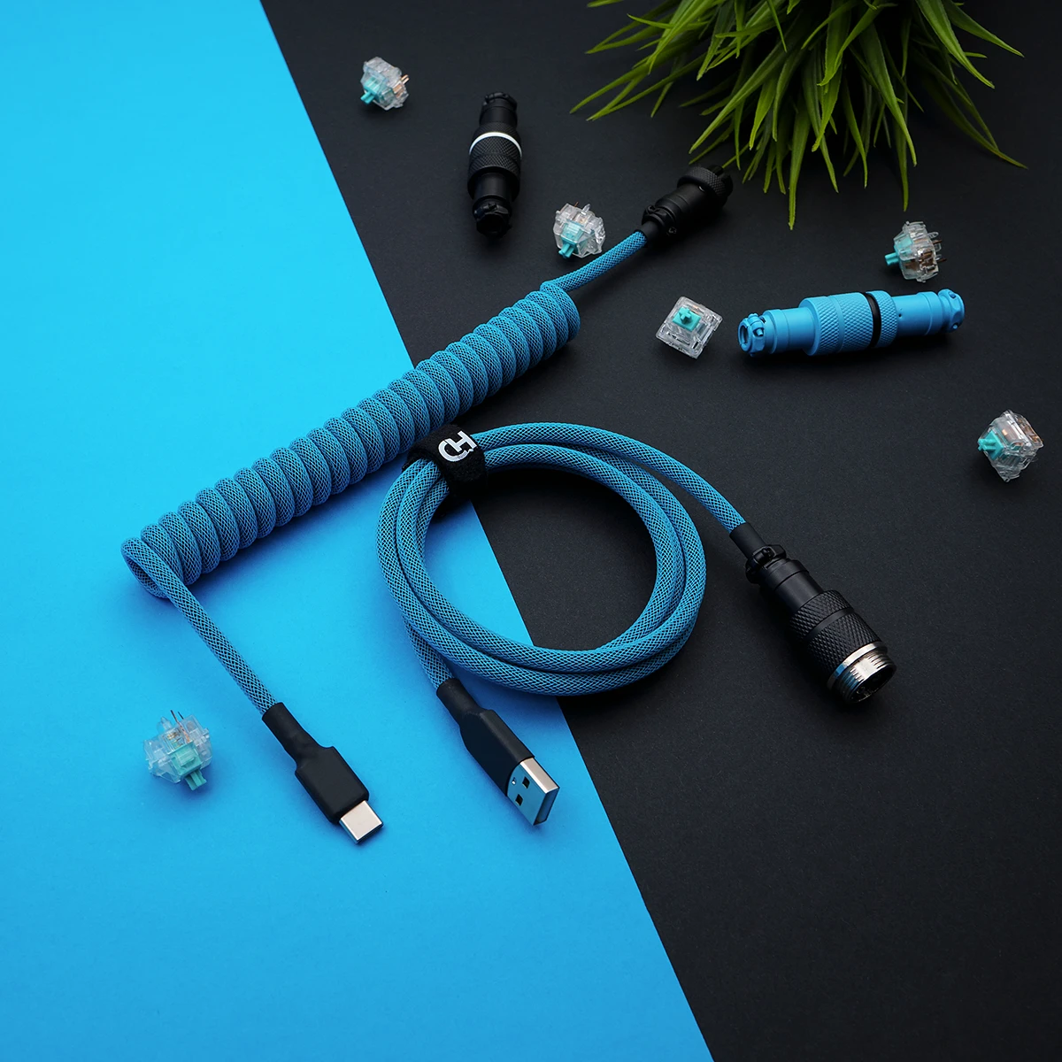 Coiled blue paracord keyboard cable featuring USB-C and GX16 connectors. High-quality finish, detachable plugs, and textured braiding enhance durability.