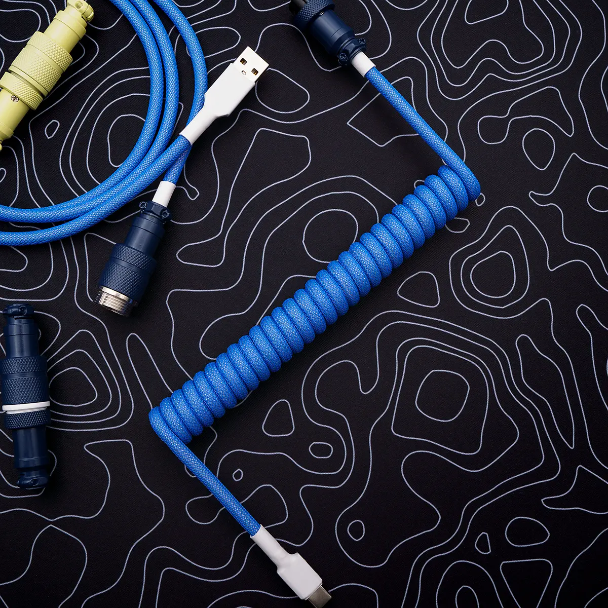 Custom blue coiled keyboard cable with a USB-C connector, featuring a durable paracord braid and detachable plugs for flexibility and style.