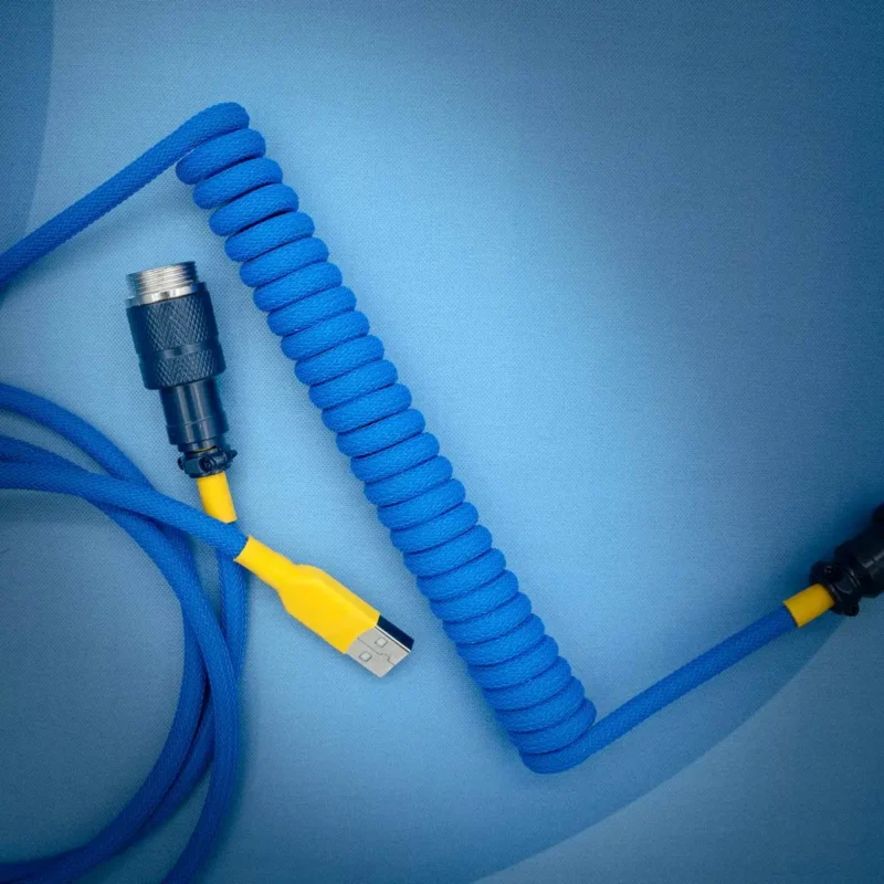 Coiled blue keyboard cable featuring a USB connector, detachable aviator end, vibrant yellow heatshrink, and durable paracord for flexibility.