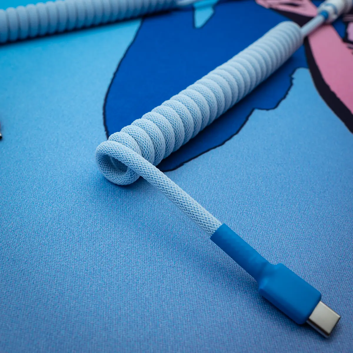 Coiled blue keyboard cable with a USB-C connector, featuring a textured paracord design and high-quality finish, perfect for custom setups.