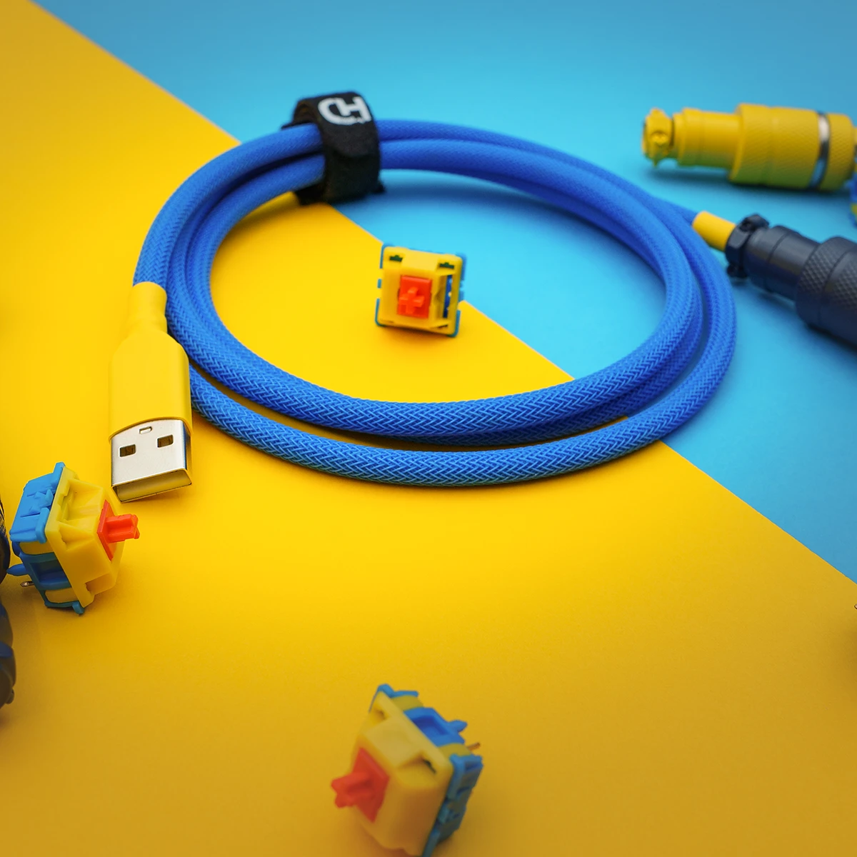 Bright blue custom keyboard cable with a yellow USB connector, featuring textured paracord braiding and detachable plugs, ideal for personalized setups.