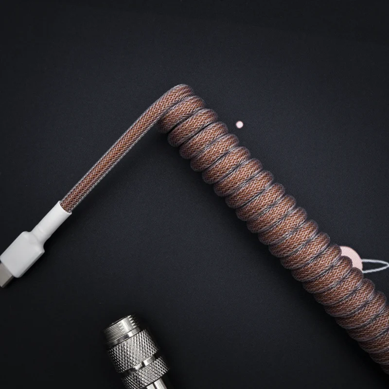 Coiled brown paracord keyboard cable with USB-C connector, featuring a sleek finish and high-quality braiding. Suitable for custom setups.