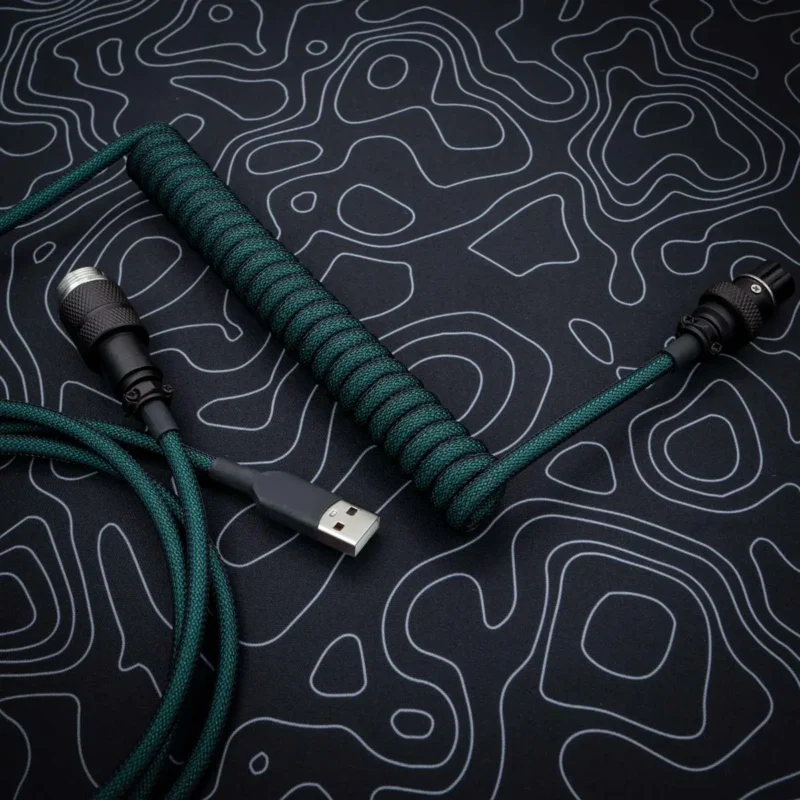 Coiled green cable with USB-A connector, detachable aviator plug, quality paracord finish, perfect for custom keyboards. Ideal for durable performance.