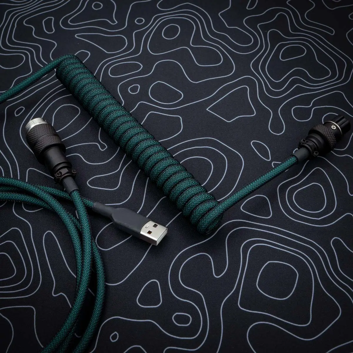 Coiled green cable with USB-A connector, detachable aviator plug, quality paracord finish, perfect for custom keyboards. Ideal for durable performance.