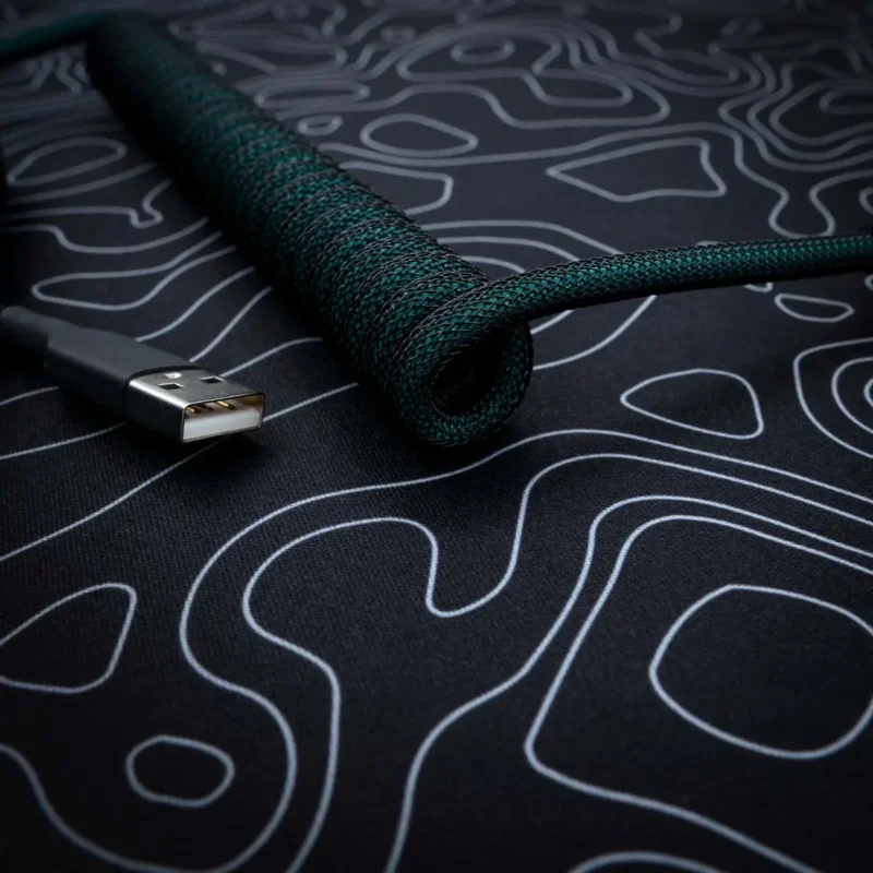 A stylish green coiled keyboard cable with a braided finish, featuring a USB connector, ideal for custom setups and high-quality connectivity.