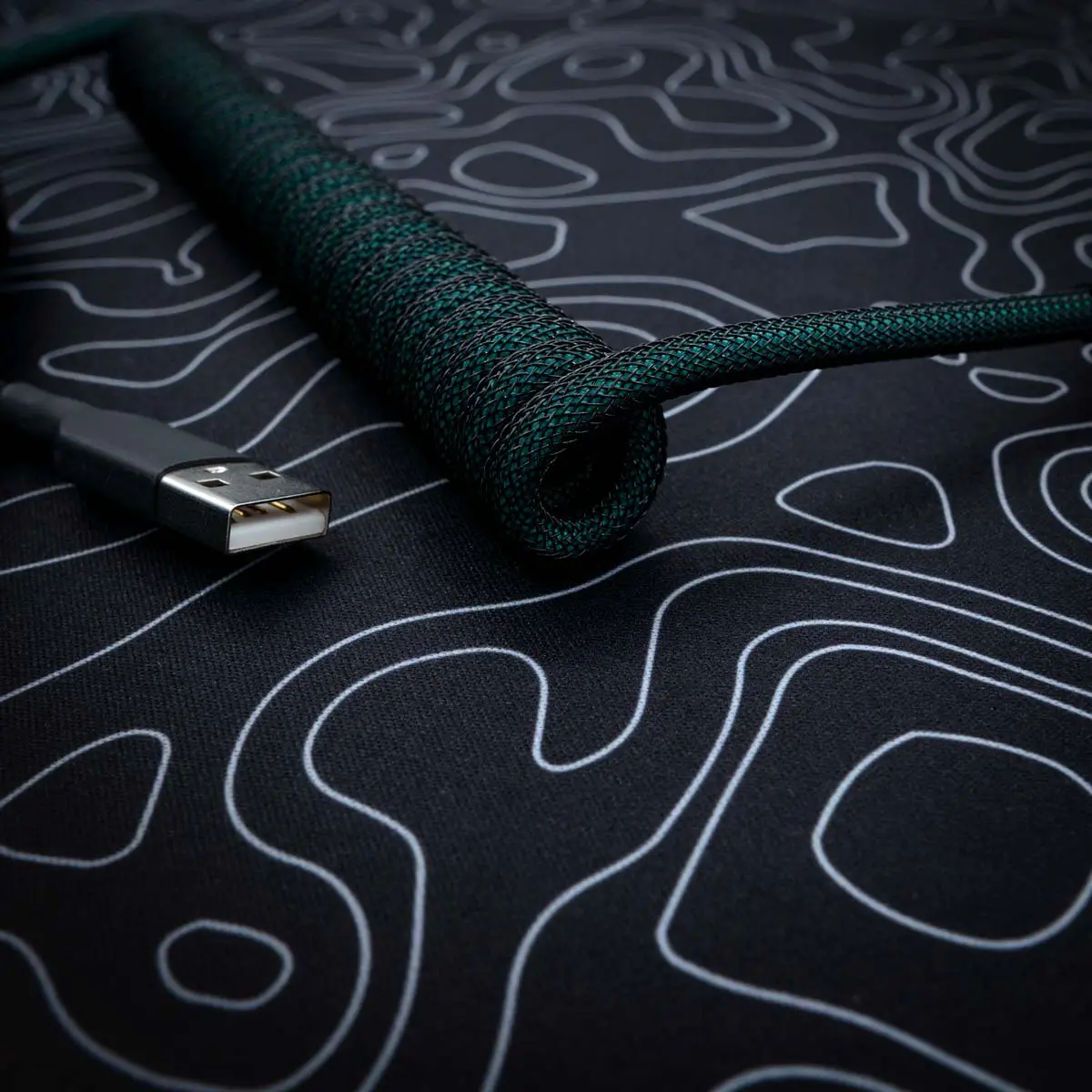A stylish green coiled keyboard cable with a braided finish, featuring a USB connector, ideal for custom setups and high-quality connectivity.