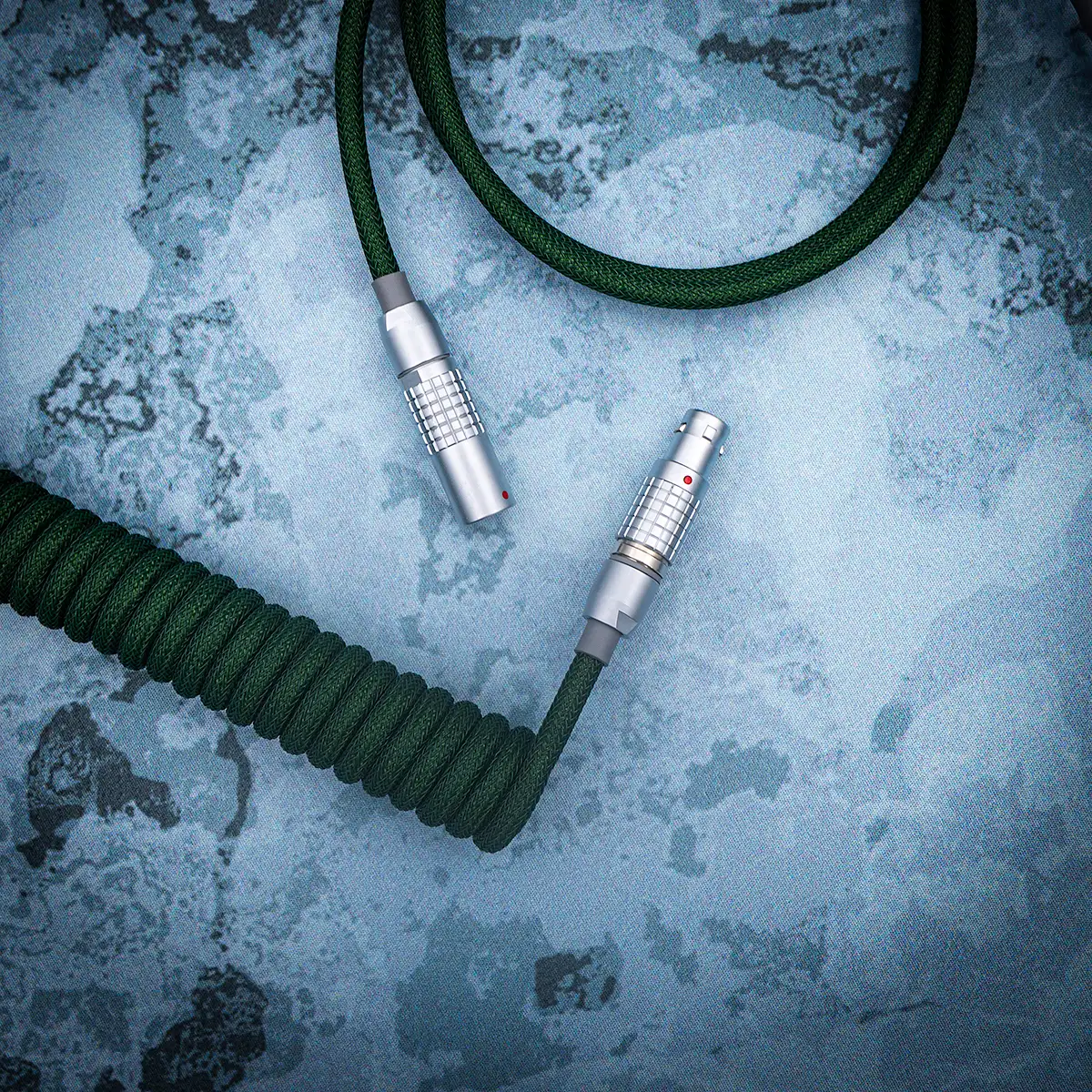 Coiled green paracord keyboard cable featuring detachable metal connectors, ideal for customizable setups; showcases premium braiding and sleek finish.