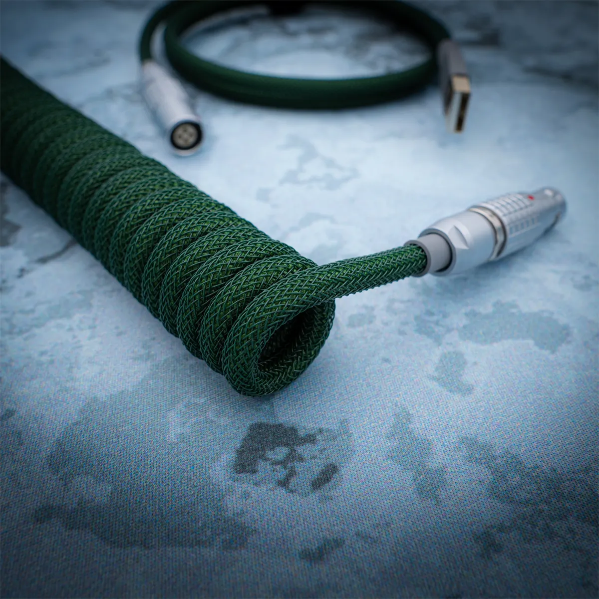Custom green paracord keyboard cable features a coiled design, USB Type-A and aviator connectors, with high-quality heatshrink and durable braiding.