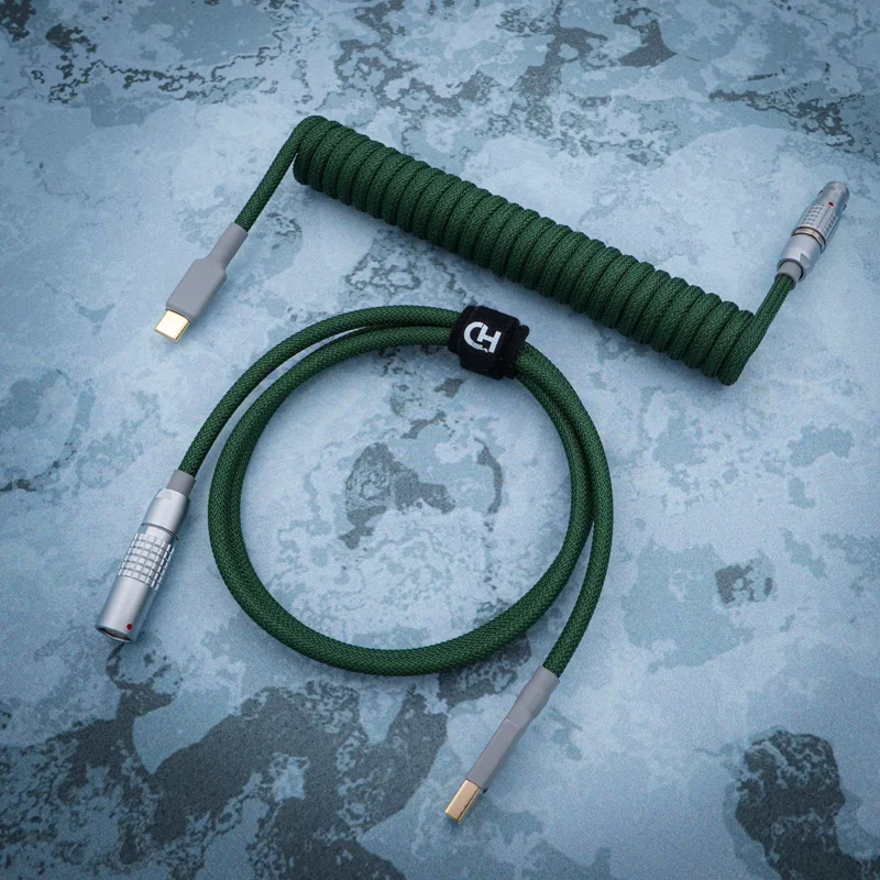 Custom green coiled keyboard cable featuring USB-C and aviator connectors, durable braided finish, heatshrink elements, and quality CNC metal housing.