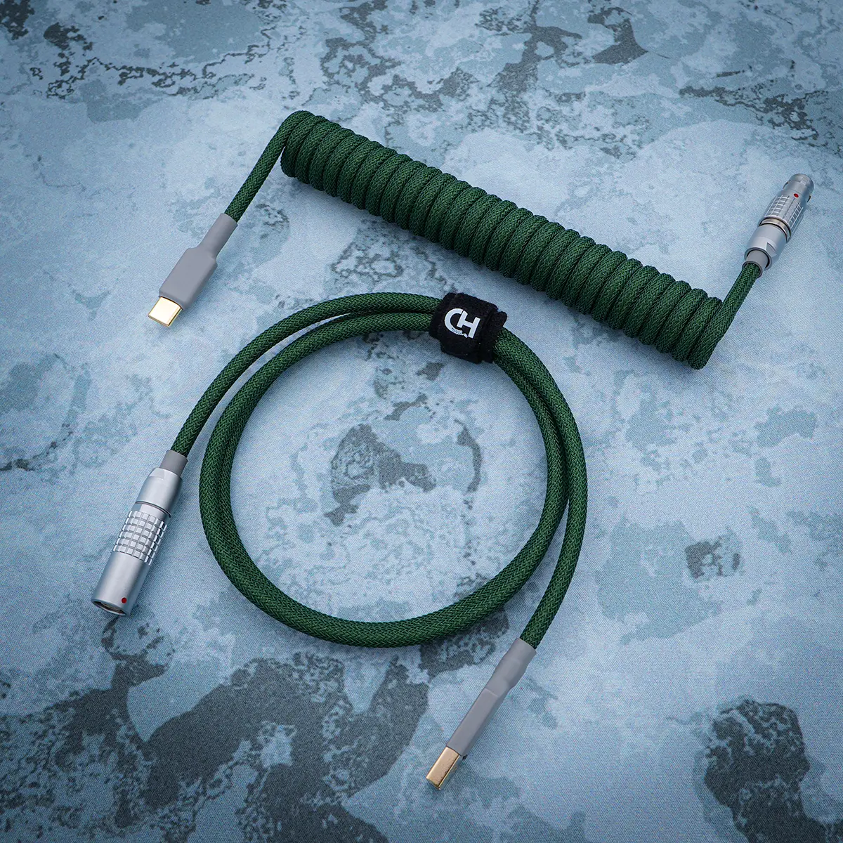 Custom green coiled keyboard cable featuring USB-C and aviator connectors, durable braided finish, heatshrink elements, and quality CNC metal housing.