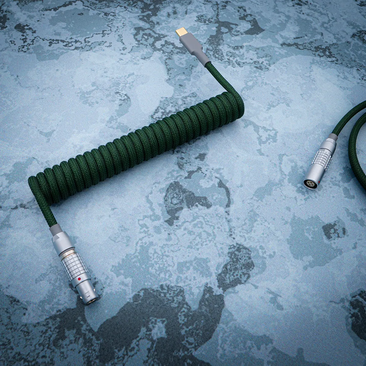 Coiled green paracord keyboard cable featuring USB-C and aviator connectors, noted for its durable braiding and high-quality CNC metal housing.