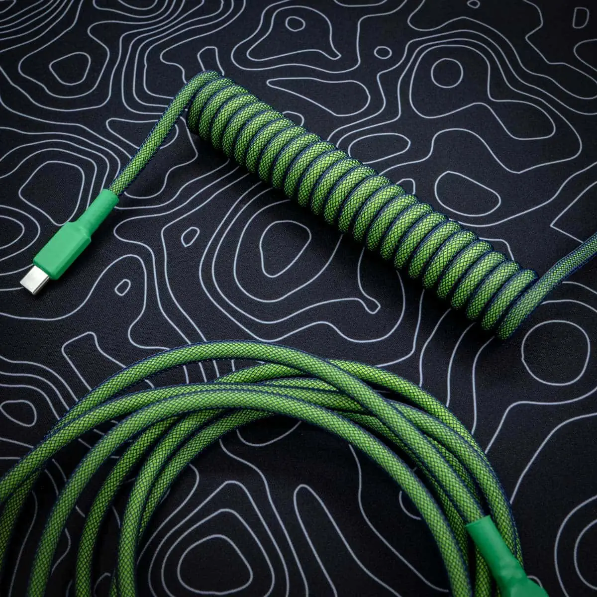 Coiled dark green keyboard cable with USB-C connector, features durable paracord, high-quality braiding, and a textured finish for style and performance.
