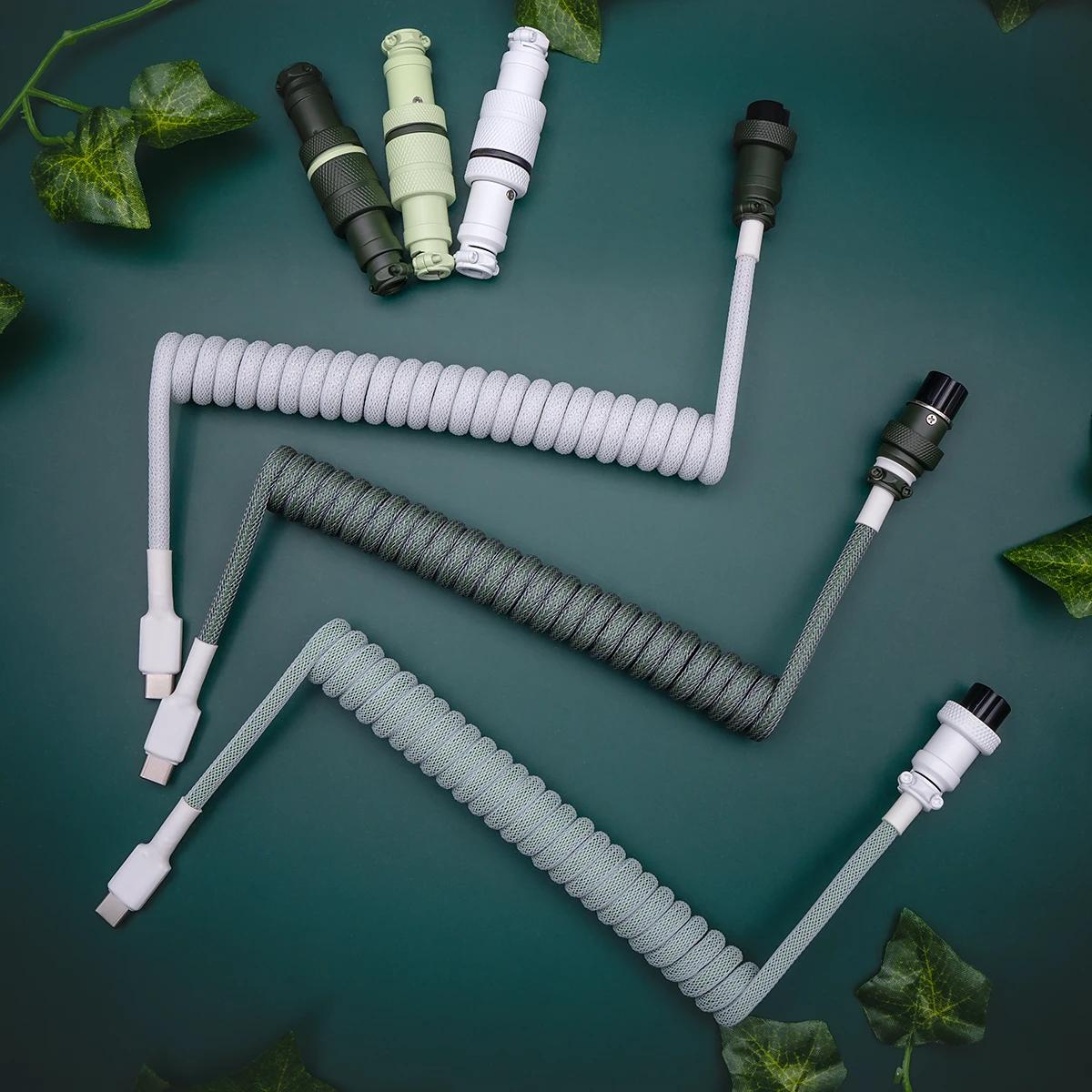 Custom coiled keyboard cables in varying shades of green and white, featuring detachable USB-C connectors and smooth paracord braiding for durability.