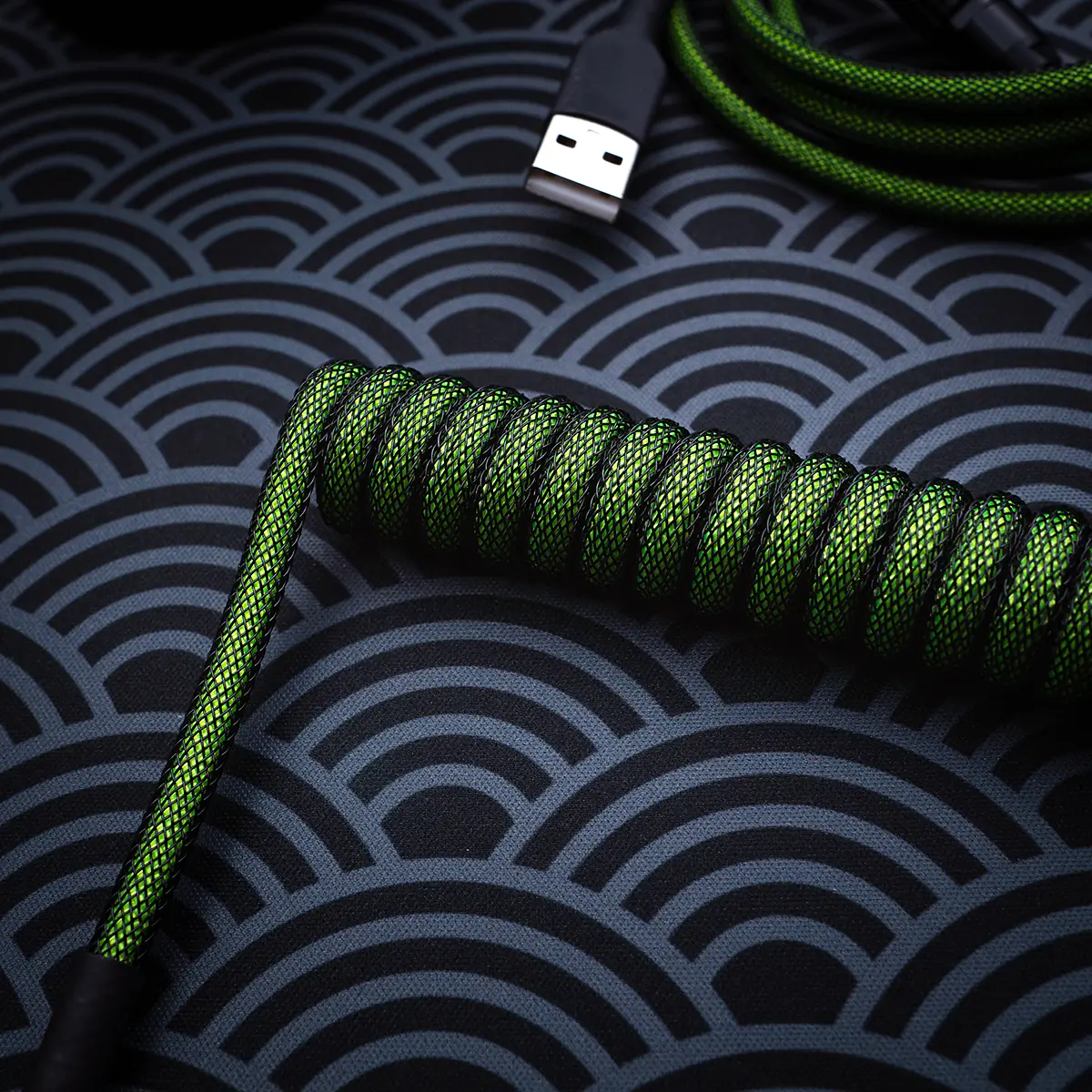 Custom green keyboard cable featuring a coiled design with high-quality braiding. Includes a USB connector and textured heatshrink for durability.