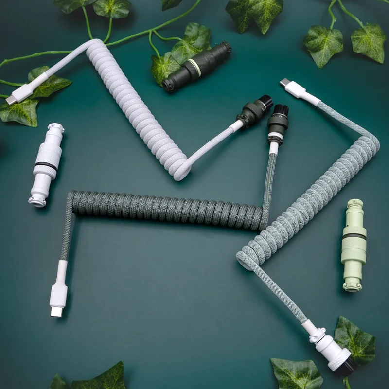 Coiled custom keyboard cables featuring USB-C and aviator connectors, with a sleek green and gray paracord finish for durability and style.