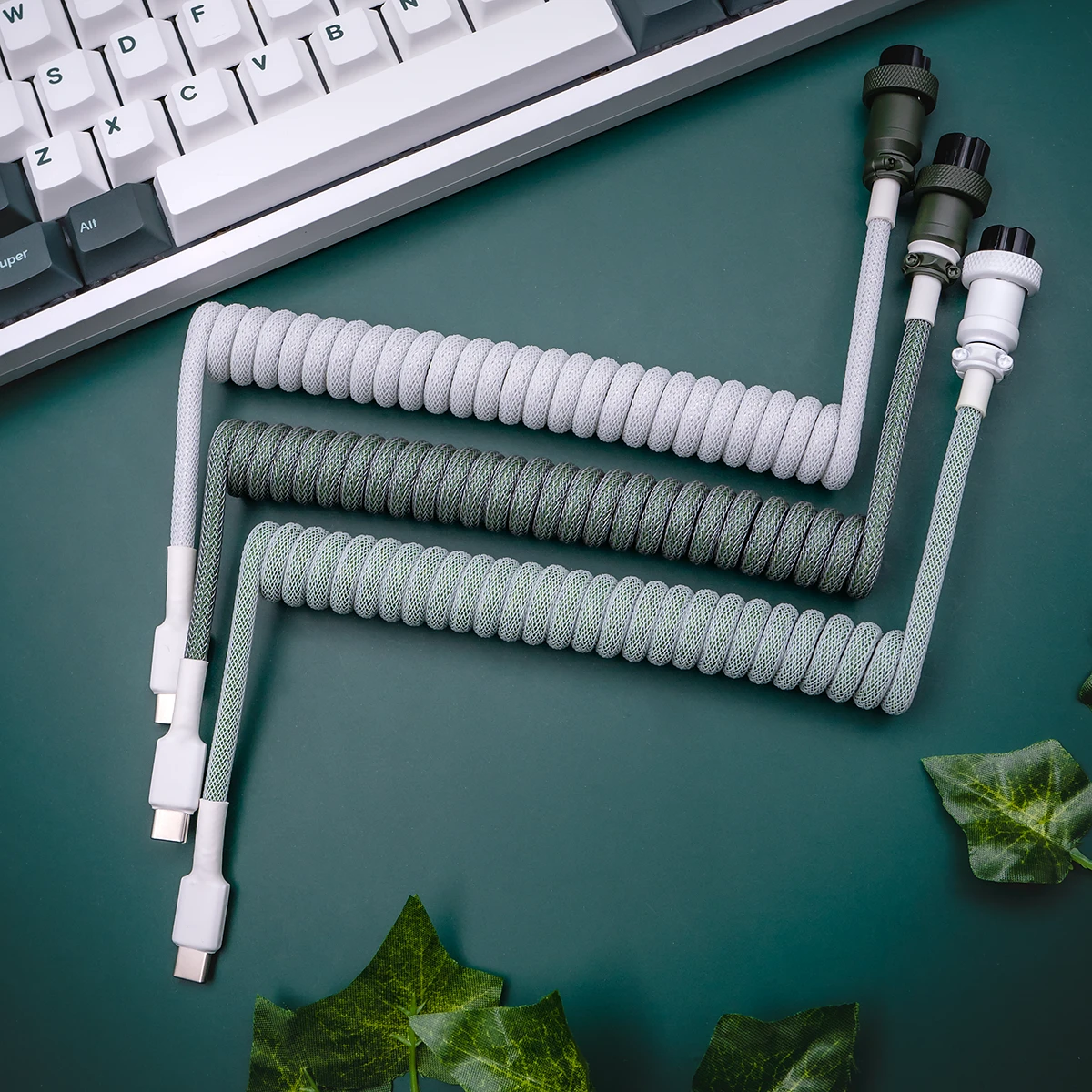 Coiled keyboard cables in gray and green paracord, featuring USB-C connectors, detachable plugs, and CNC metal housing for premium quality and durability.