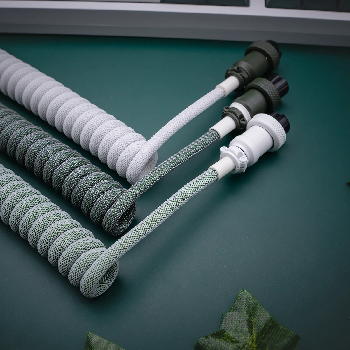 Custom keyboard cables in a botanical theme, featuring coiled designs in gray and green, nylon braiding, and detachable connectors for easy use.