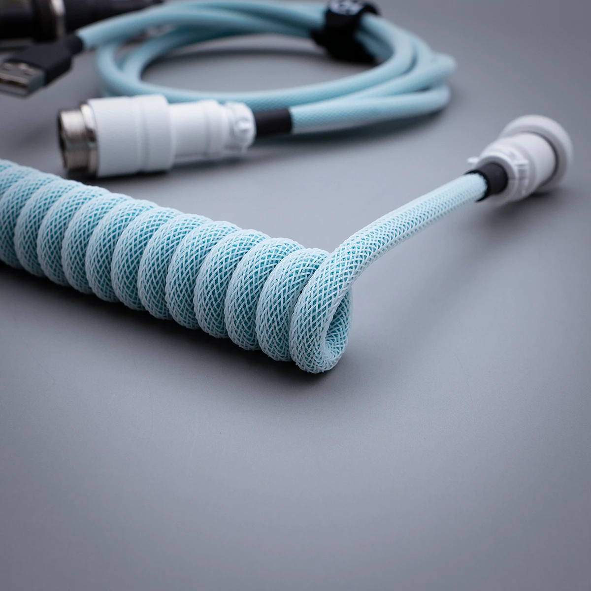 Coiled blue keyboard cable featuring high-quality braiding, a detachable connector with a metal housing, and a smooth finish for durability.