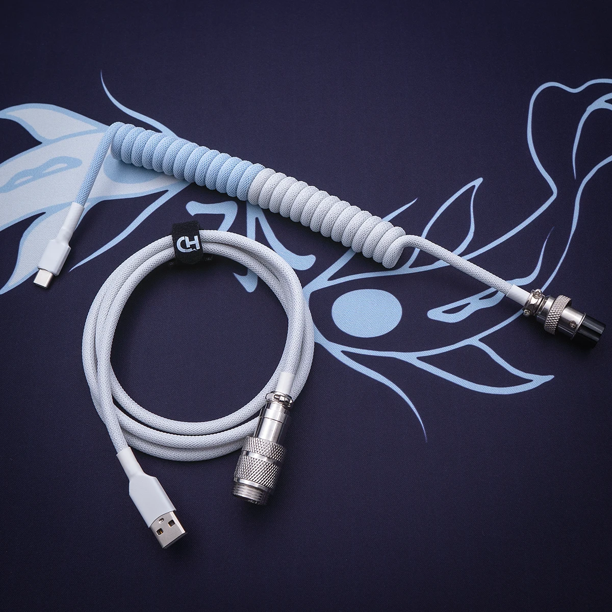Custom keyboard cable featuring a coiled design in a soft blue and gray color scheme. Includes USB-C and aviator connectors with durable braiding and quality finish.