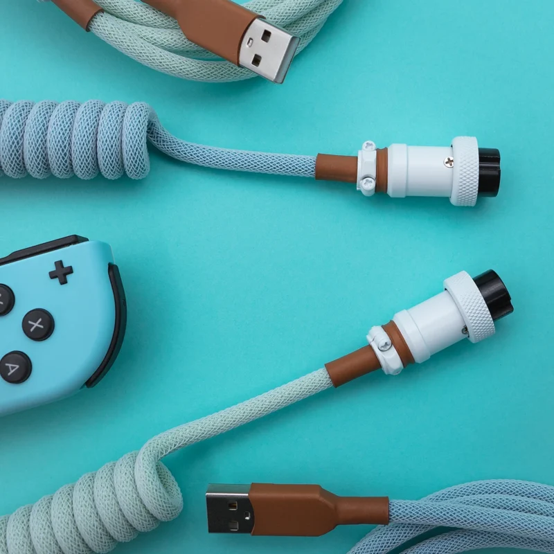 Coiled PBT Islander keyboard cable features a light blue and brown paracord design, USB-C and aviator connectors with durable CNC metal housing, perfect for custom setups.