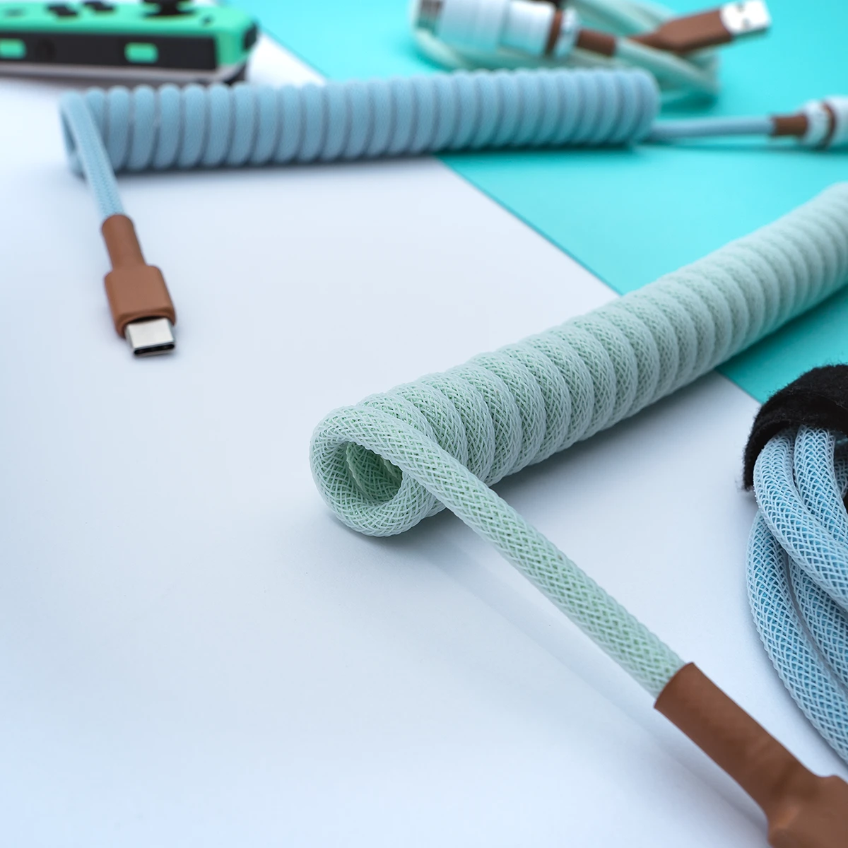 Curled mint green coil cable with a USB-C connector. Features a durable paracord finish, ensuring flexibility and style for custom keyboard setups.