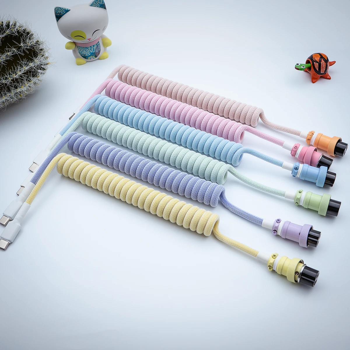 A vibrant collection of coiled keyboard cables featuring USB-C and aviator connectors, highlighted by colorful paracord braiding and quality finishes.