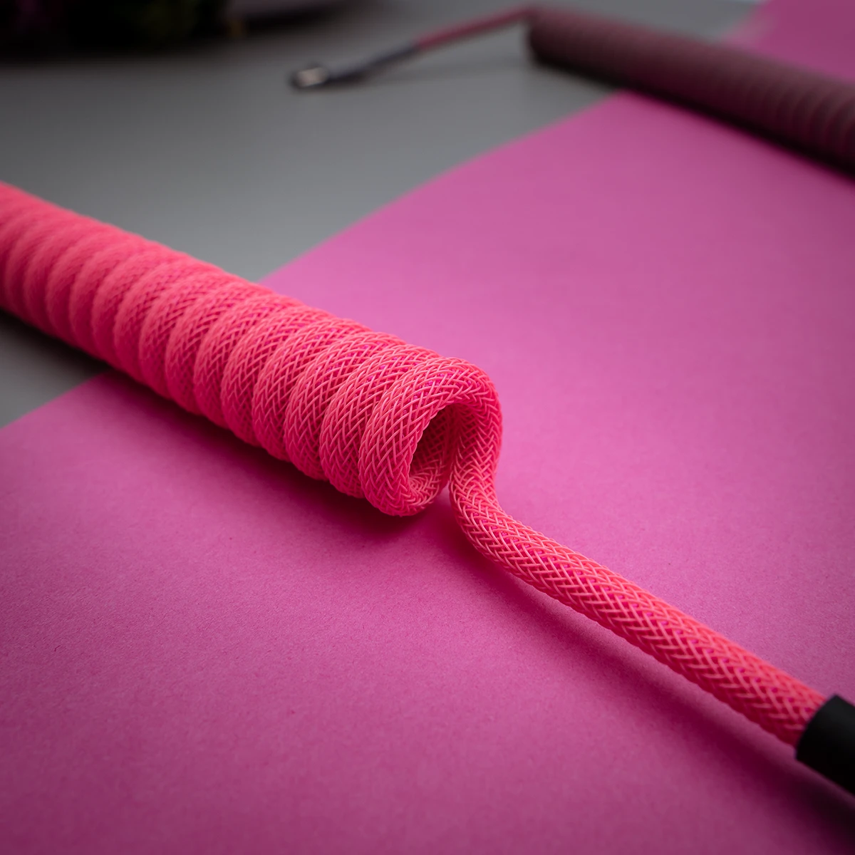 Custom keyboard cable featuring a vibrant pink paracord design with a coiled section, smooth braiding, and a sturdy heatshrink finish.