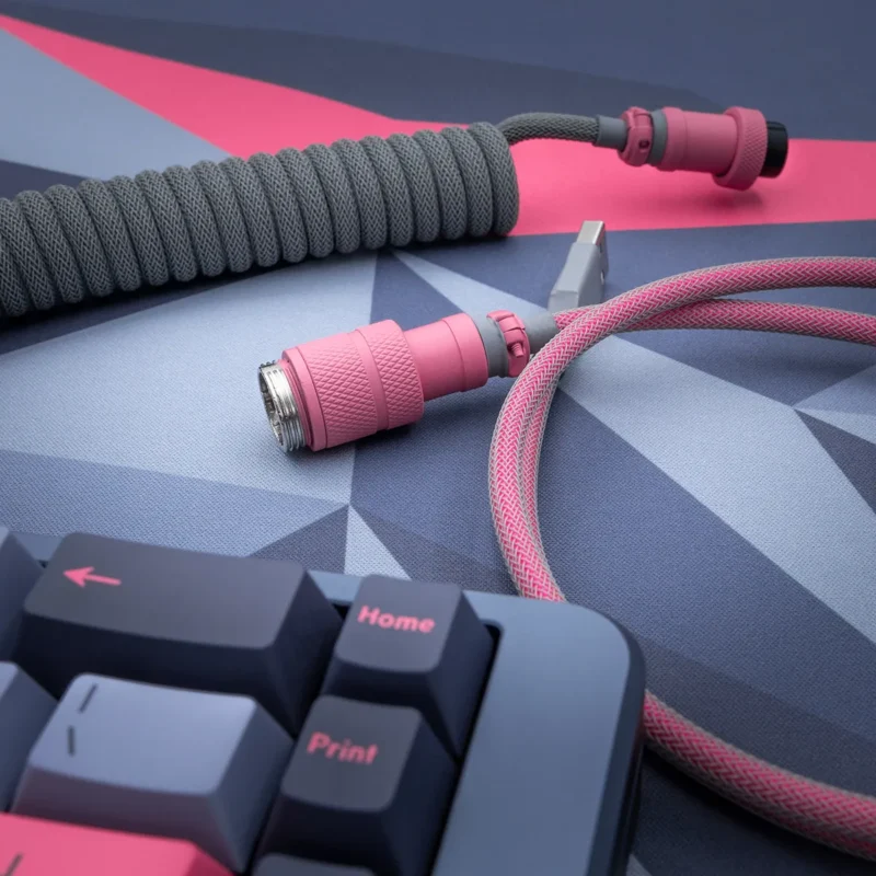 Custom keyboard cable featuring a coiled gray paracord with pink accents, detachable aviator plugs, and quality braiding for durability.