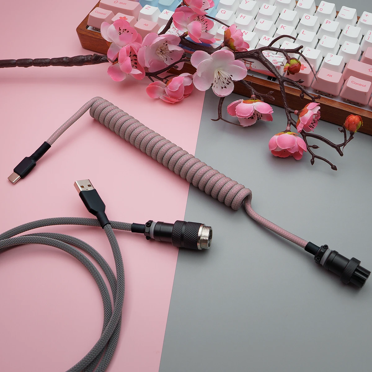 Coiled pink paracord keyboard cable with USB-C and aviator connectors. Features quality braiding and detachable plugs for flexibility and style.