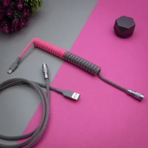 Coiled keyboard cable with pink and gray paracord, featuring USB-C and aviator connectors, showcasing high-quality braiding and finishes.