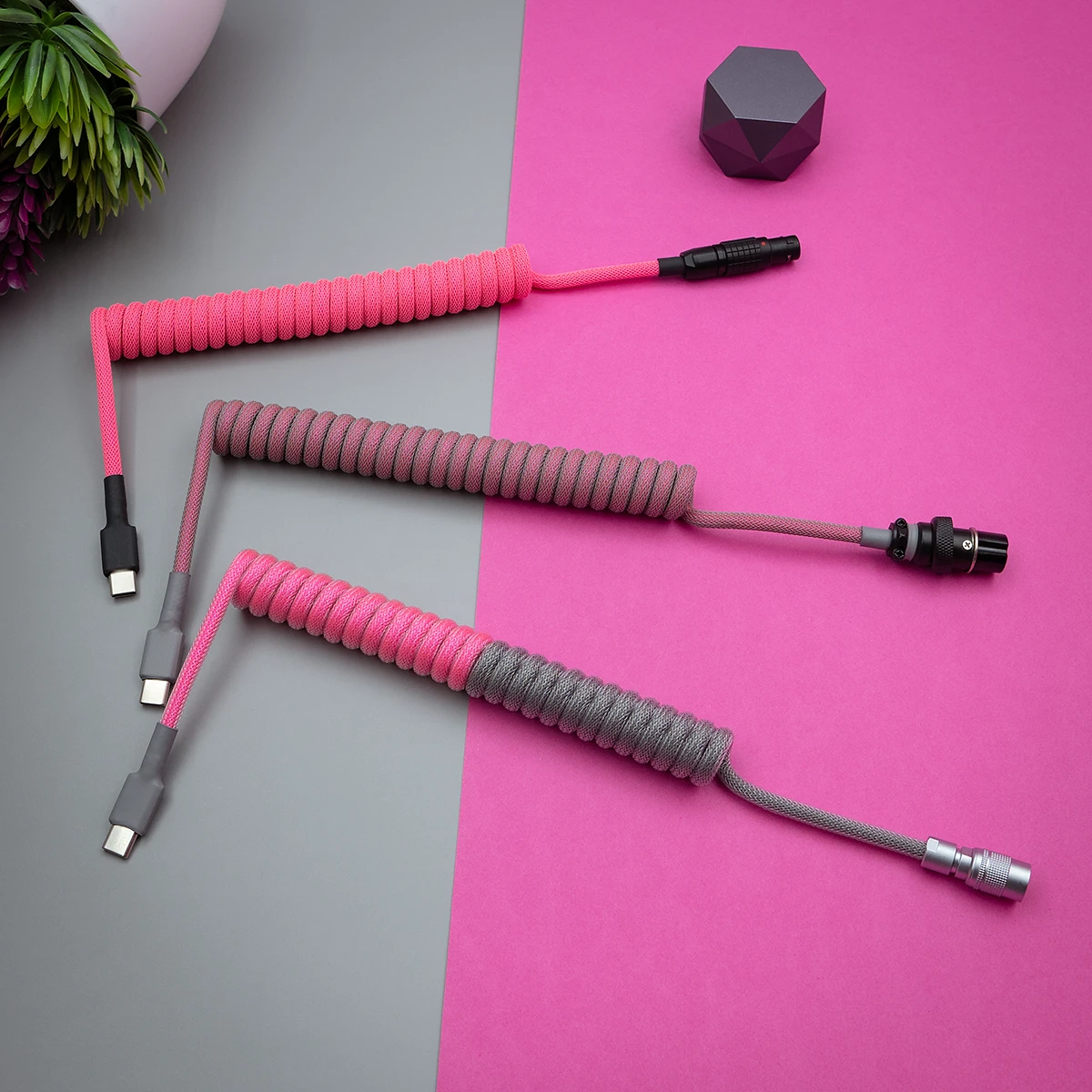 Three custom keyboard cables feature vibrant pink and gray paracord braiding. Each has detachable connectors: USB-C, micro-USB, and aviator style.