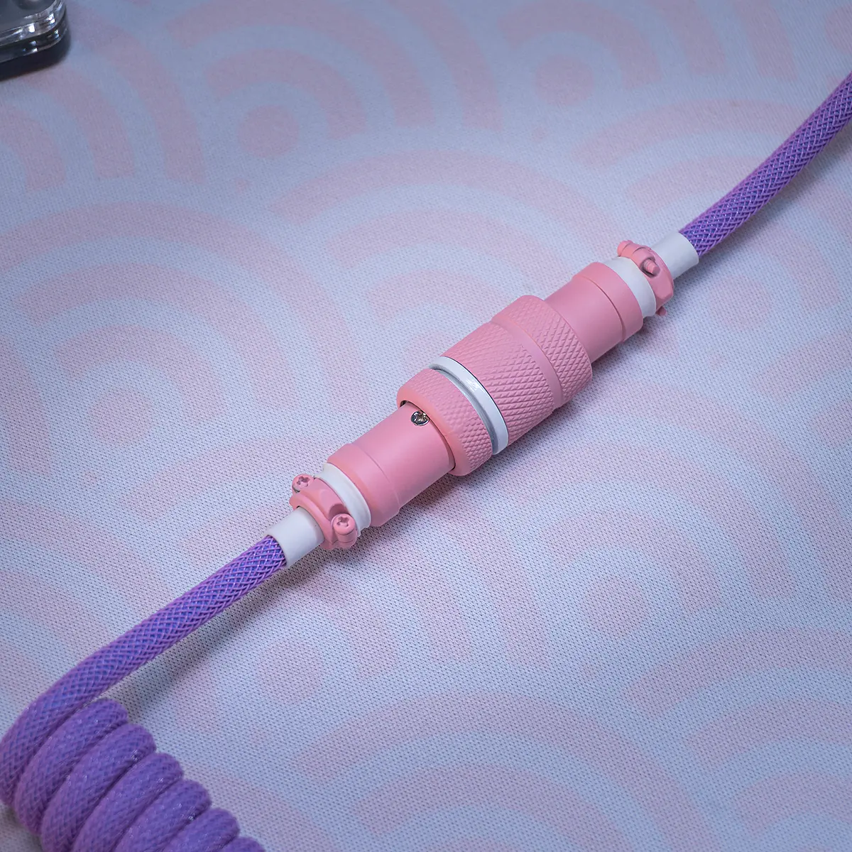 Coiled keyboard cable featuring a vibrant purple paracord design, detachable USB-C connector, and a stylish pink CNC metal housing with textured finish.