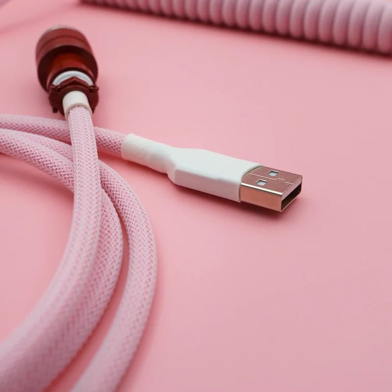 Custom pink keyboard cable featuring a coiled design, USB-A connector, and braided paracord for durability and style, perfect for any setup.