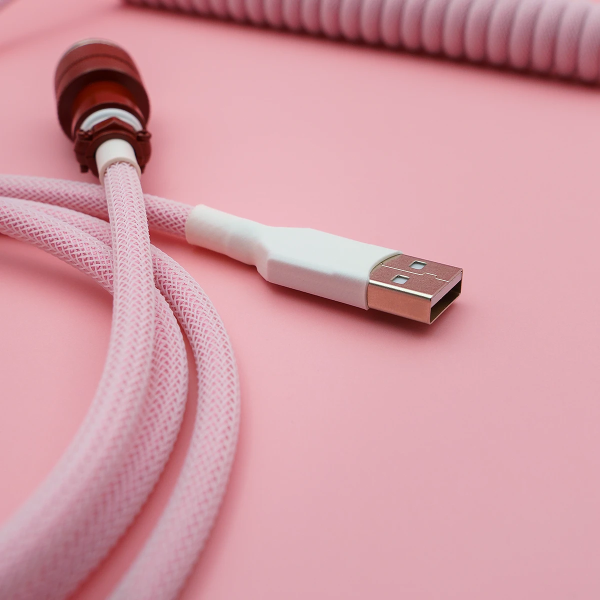 Custom pink keyboard cable featuring a coiled design, USB-A connector, and braided paracord for durability and style, perfect for any setup.