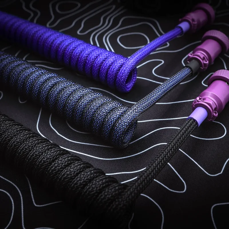 Coiled custom keyboard cables showcase vibrant purples and blacks with textured braiding. Features include detachable connectors and quality craftsmanship details.