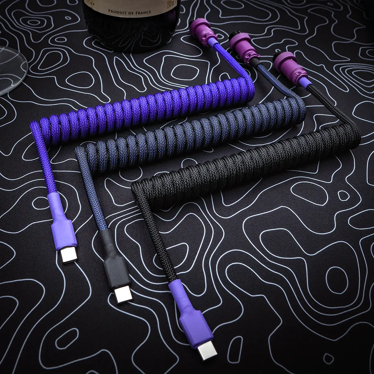 Custom keyboard cables featuring coils in purple and black paracord, USB-C connectors, and sleek detachable plugs, designed for style and durability.