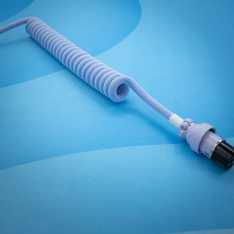 A delicate purple coiled keyboard cable with a smooth finish, featuring a sturdy aviator connector and detailed paracord braiding for durability.