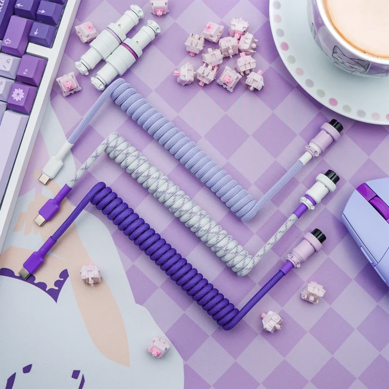 A set of custom keyboard cables featuring coiled designs in purple and lavender, USB-C and aviator connectors, and a sleek, braided finish for durability.