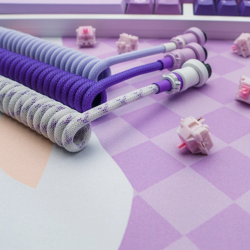 Custom keyboard cables in purple and white paracord, featuring coiled sections, detachable connectors, and high-quality CNC metal housing.