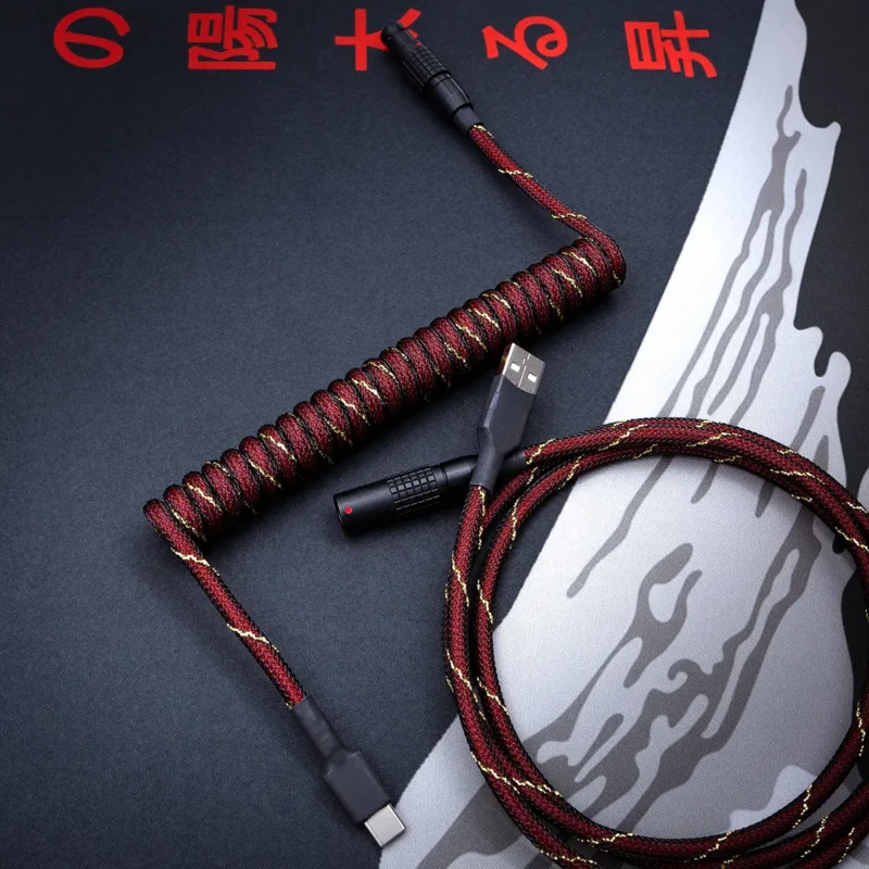 Custom keyboard cable featuring a coiled design with rich red and gold paracord finish, USB-C and aviator connectors, and high-quality braiding.