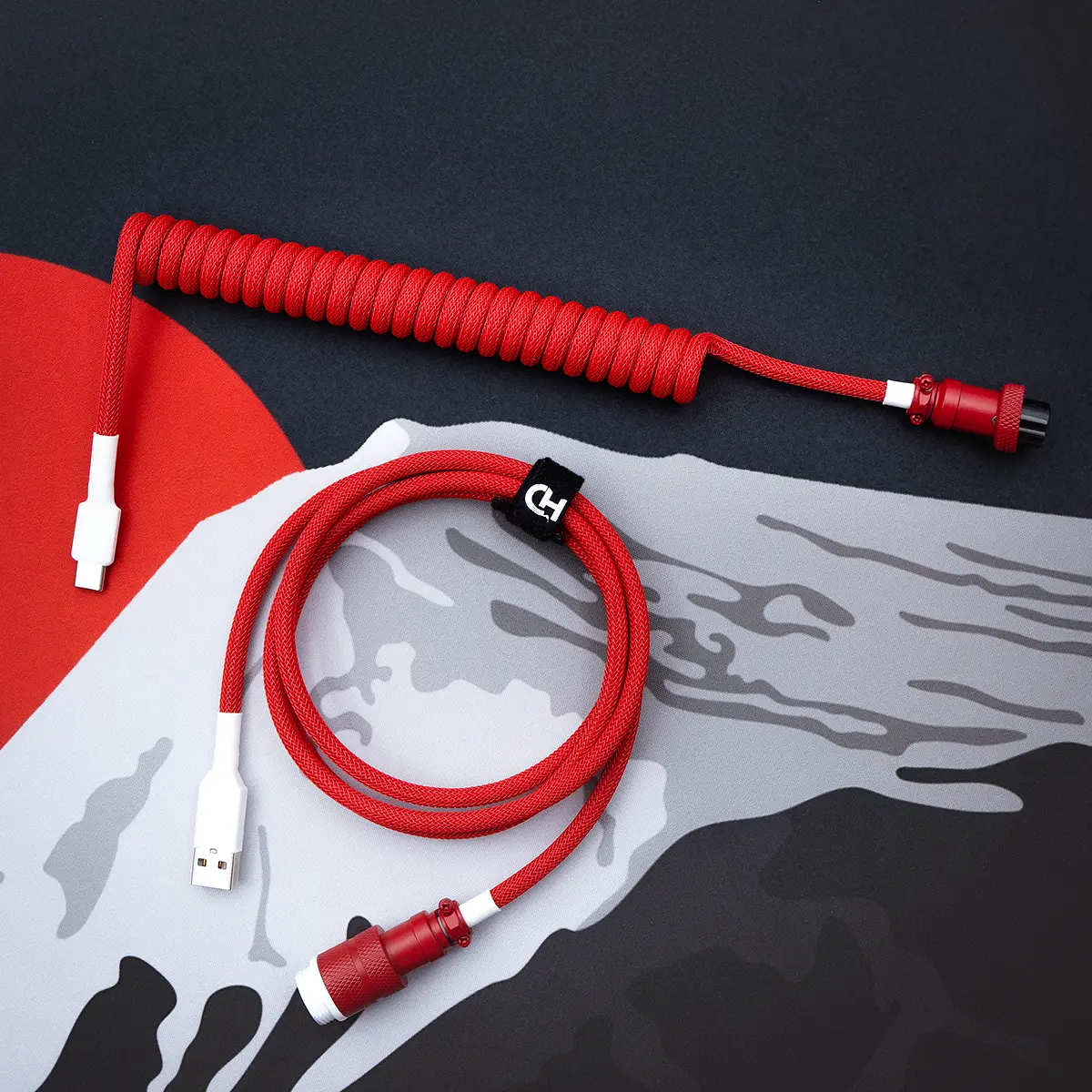 A vibrant red keyboard cable features a coiled segment and a straight section with a USB-C connector, showcasing quality paracord braiding and CNC metal housing.