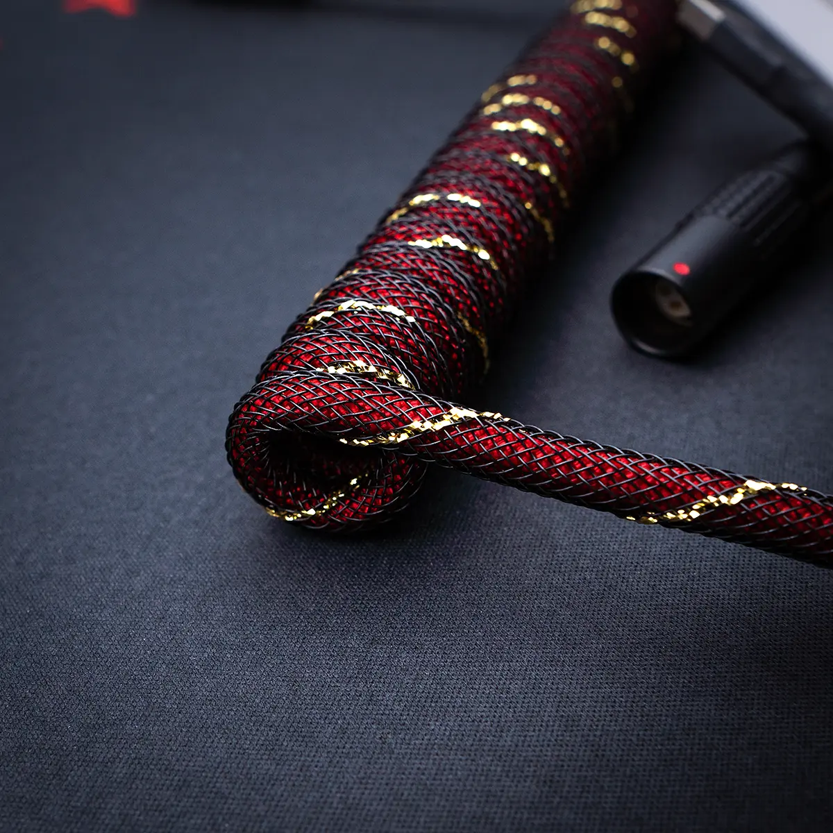 A coiled red and black braided keyboard cable, featuring gold accents, USB-C connectors, and a high-quality finish, perfect for custom setups.