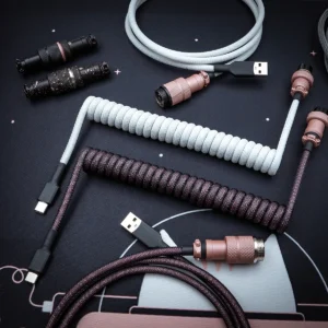 Coiled and straight keyboard cables in light gray and dark purple, featuring USB-C connectors, detachable plugs, and a textured paracord finish.